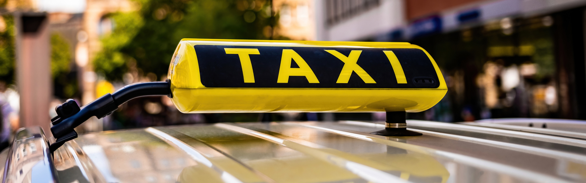 Nahaufnahme eines gelben Taxischildes, das auf dem Dach eines Fahrzeugs in einer städtischen Umgebung montiert ist und das Wesen der geschäftigen Straßen Erdings einfängt.