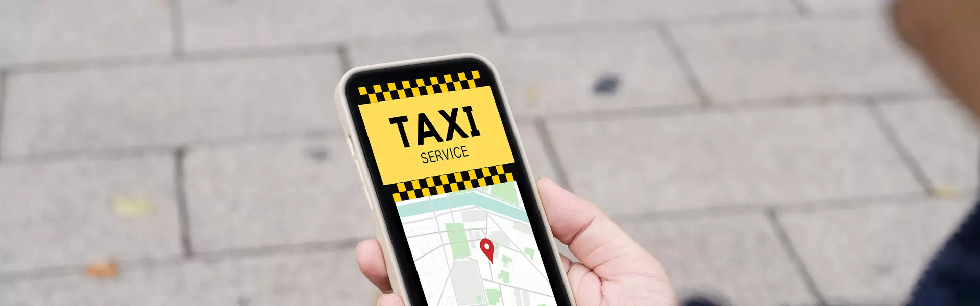 Nahaufnahme einer Hand, die ein Smartphone hält, auf dessen Bildschirm eine Taxiservice-App mit einer Karte und einer Standortnadel für Erding angezeigt wird.